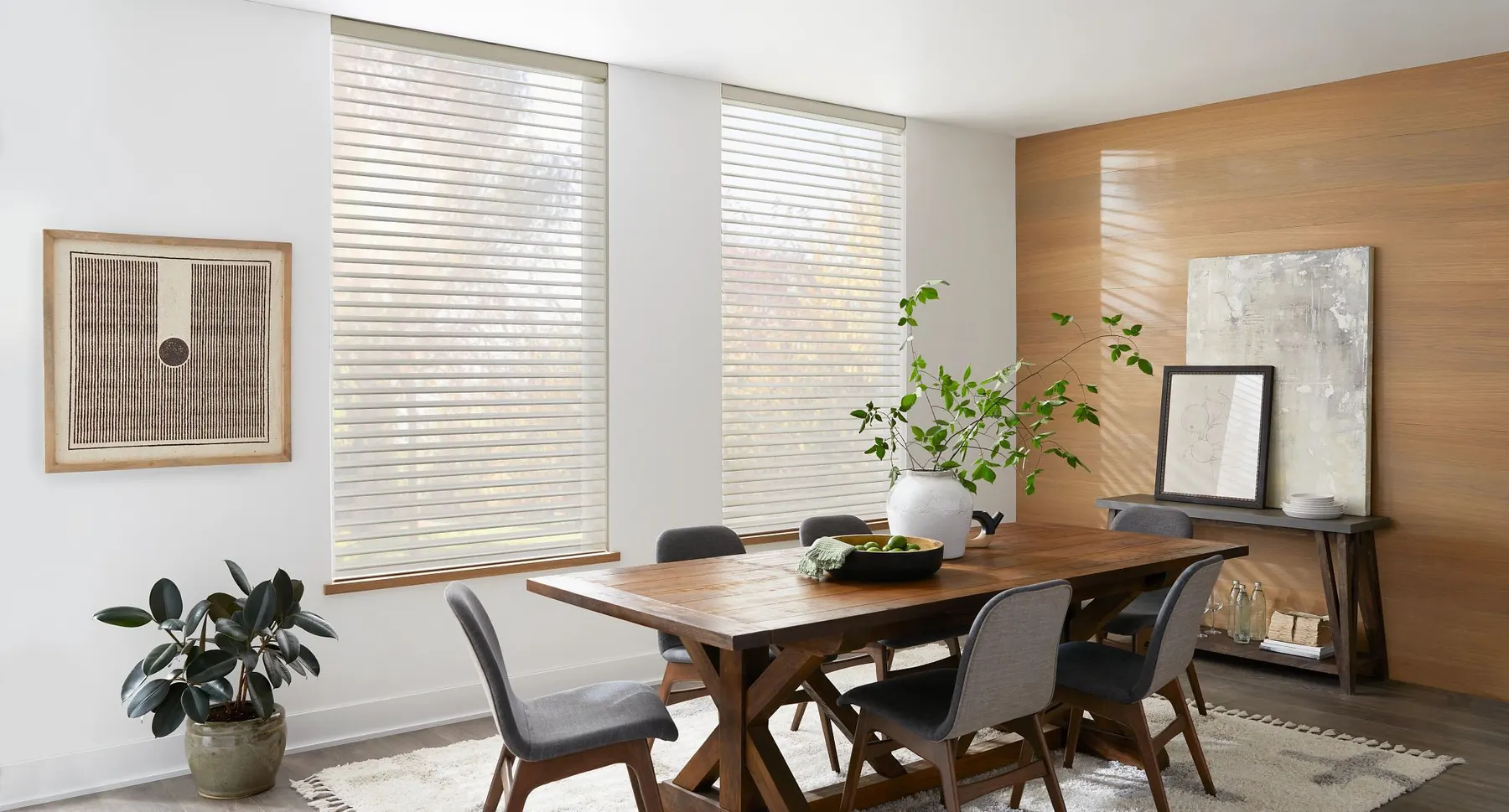White sheer shadings on two tall windows softening the daylight over a farmhouse dining table.