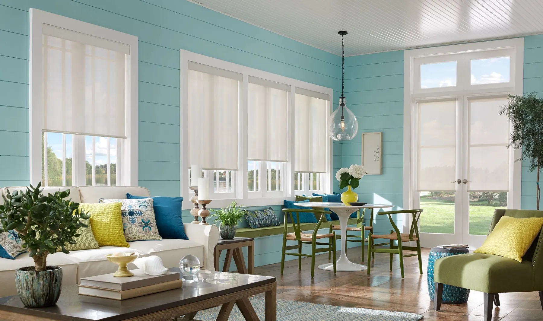 Light-filtering roller shades on the windows and French doors of a sunroom with turquoise shiplap walls.
