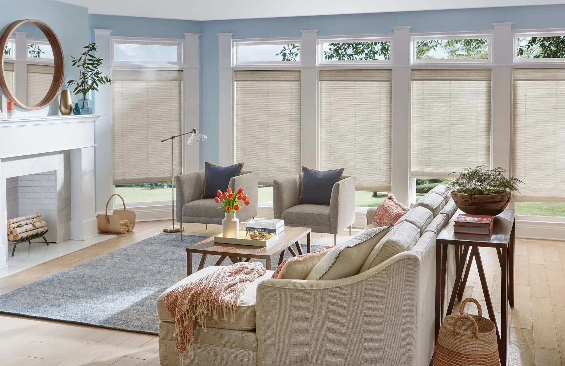 Natural woven shades on a long wall of windows with transoms in a light blue living room.